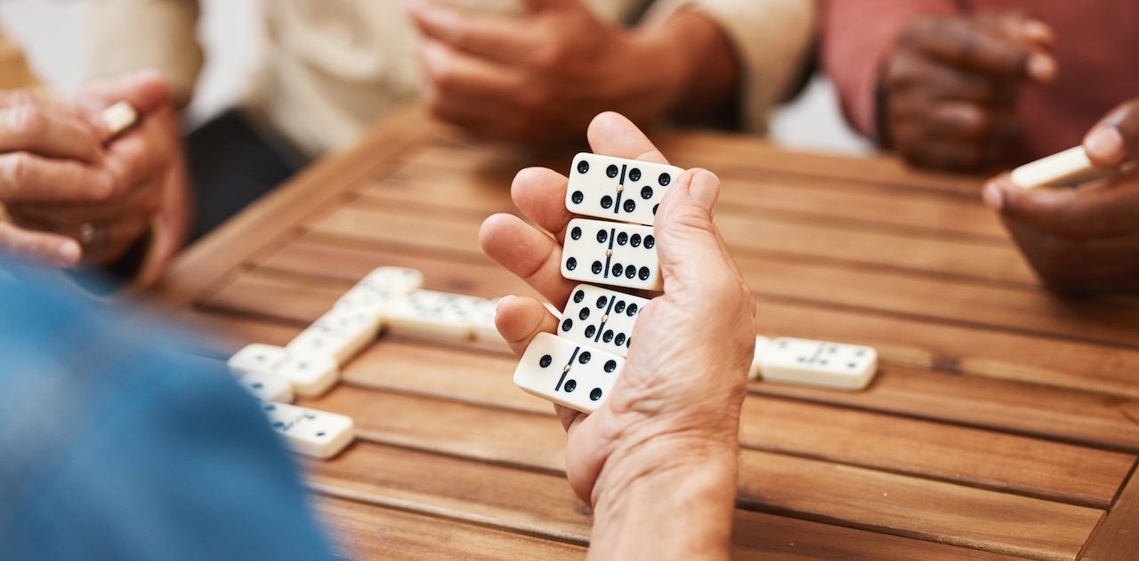 A domino player holding four dominoes in the palm of their hand.