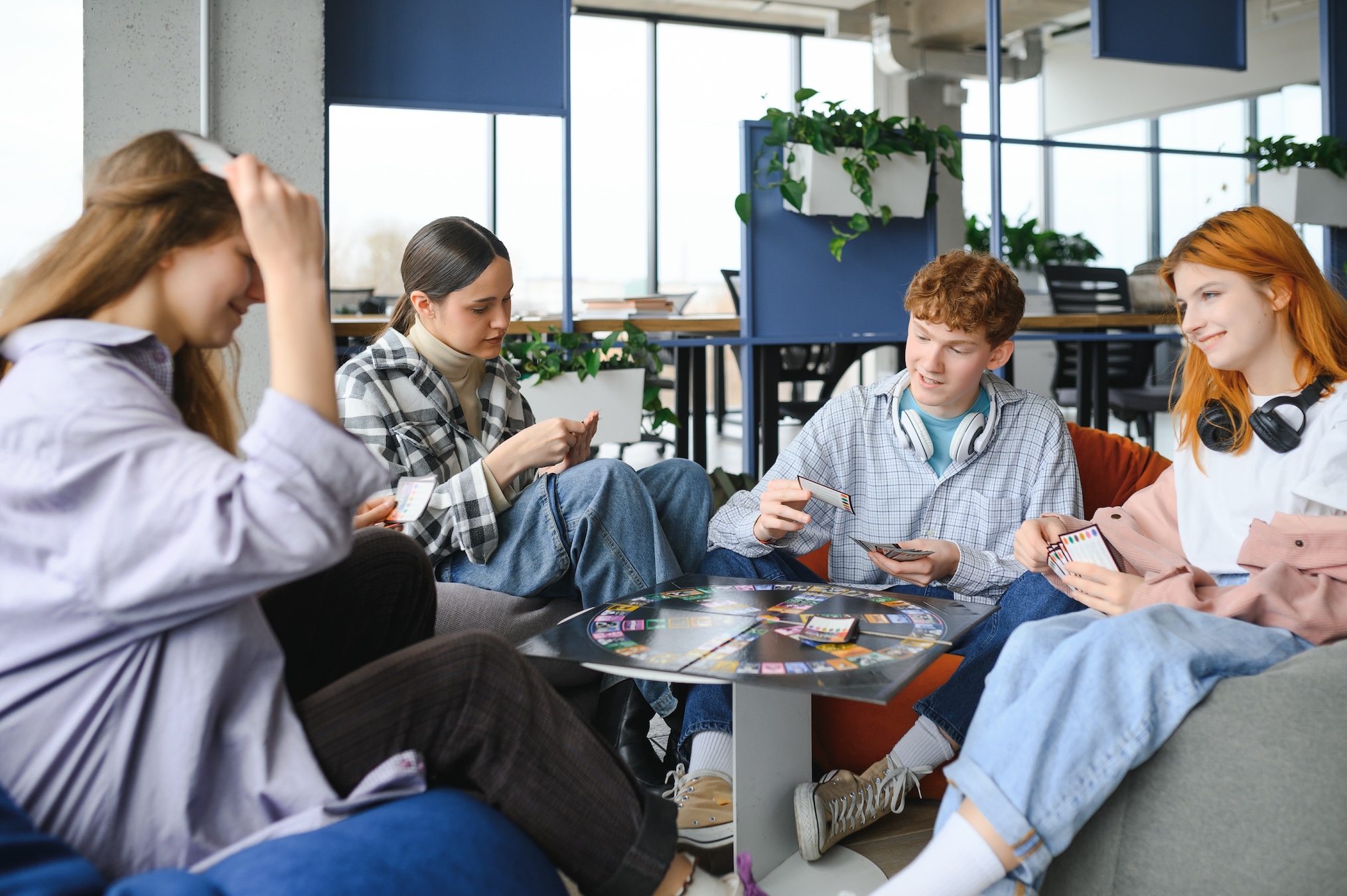 Group of young adults sitting together and playing a card-based board game at a casual game club meetup in a modern shared space.